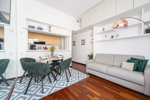 A modern living room with a sofa and chairs, a dining area with a table and chairs, and a kitchen area with cabinets and appliances. - S Marco - Bright Central 1bdr With Balcony in Brera (Milan)