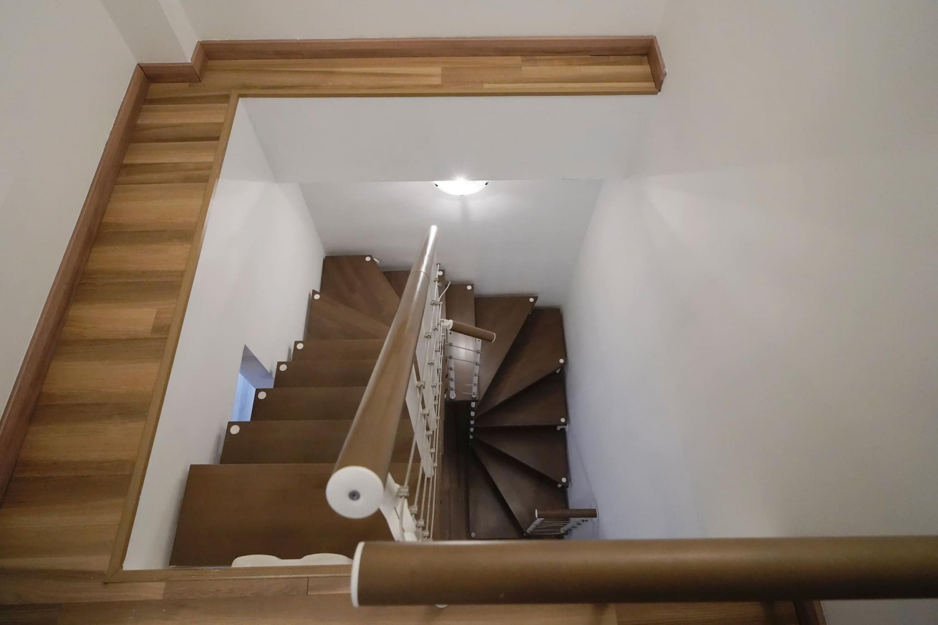Una scala in legno con corrimano e un lampadario sopra.