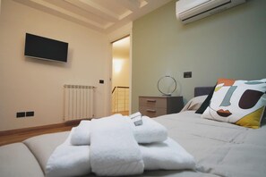 Une chambre d’hôtel équipée d’un lit, d’un téléviseur à écran plat fixé au mur, d’une table de chevet avec un miroir et d’un radiateur.
