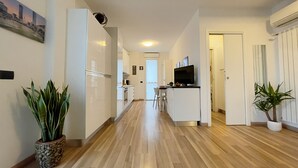 A modern kitchen with white cabinets, a built-in oven, and a TV on the counter. - Candiani Building - Modern 2BR Apartment Steps From Bovisa Politecnico (Milan)