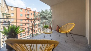 A balcony with yellow chairs, a glass table, and potted plants. - Candiani Building - Modern 2BR Apartment Steps From Bovisa Politecnico (Milan)