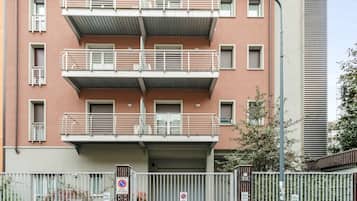 Un edificio residencial de varios pisos con balcones, una entrada con portón y una farola.