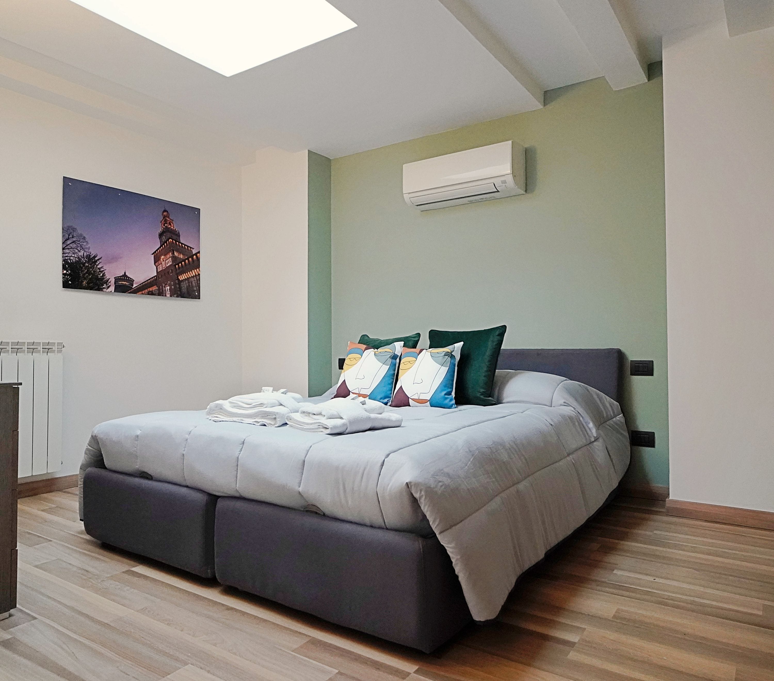 Un dormitorio moderno con cama, almohadas y un equipo de aire acondicionado en la pared.