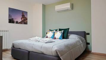 Un dormitorio moderno con cama, almohadas y un equipo de aire acondicionado en la pared.
