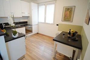 Une cuisine moderne avec des meubles blancs, un plan de travail noir et un coin repas comprenant une table et des chaises.