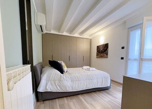 A bedroom with a bed, a wardrobe, a radiator, a painting, and a window. - Candiani Building - Modern 2BR Apartment Steps From Bovisa Politecnico (Milan)