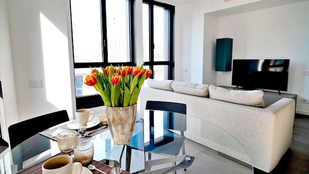 A modern living room with a glass table, a white sofa, and a flat-screen TV. - S Babila Central Tower w Rooftop Terrace in San Babila (Milan)