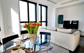 A modern living room with a glass table, a white sofa, and a flat-screen TV. - S Babila Central Tower w Rooftop Terrace in San Babila (Milan)
