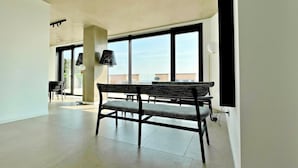 A spacious room with large windows, a bench, and a table. - S Babila Central Tower w Rooftop Terrace in San Babila (Milan)