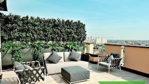 A rooftop terrace with a sofa, chairs, and a green mat. - S Babila Central Tower w Rooftop Terrace in San Babila (Milan)