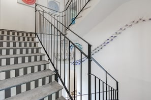 Eine Treppe mit schwarzen Geländern und einer Wand mit Musterung.