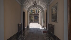 En gang med flisegulv, hvælvet loft og et skilt med 'LUJO'.