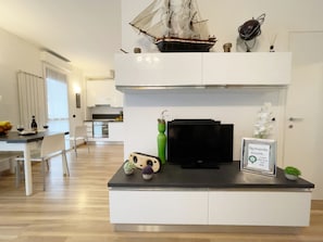 A modern kitchen with a flat-screen TV, a ship model, and a framed welcome sign. - Candiani D3 Bilocale 2 Livelli (Milan)