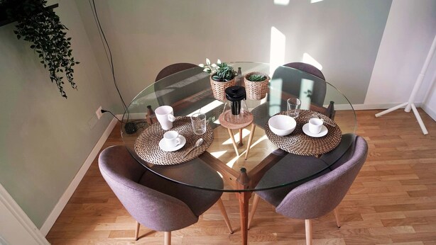 A round glass table with two purple chairs, two woven placemats, and two small potted plants. - Solferino - Elegant 1bdr in Historical Building in Brera (Milan)