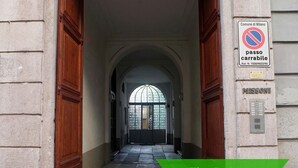A building entrance with a no parking sign, a nameplate, and a green banner. - Solferino - Elegant 1bdr in Historical Building in Brera (Milan)