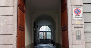 A building entrance with a no parking sign, a nameplate, and a green banner. - Solferino - Elegant 1bdr in Historical Building in Brera (Milan)