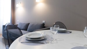 Un coin repas avec une table ronde dressée pour deux personnes, comprenant des assiettes, des verres et des couverts.