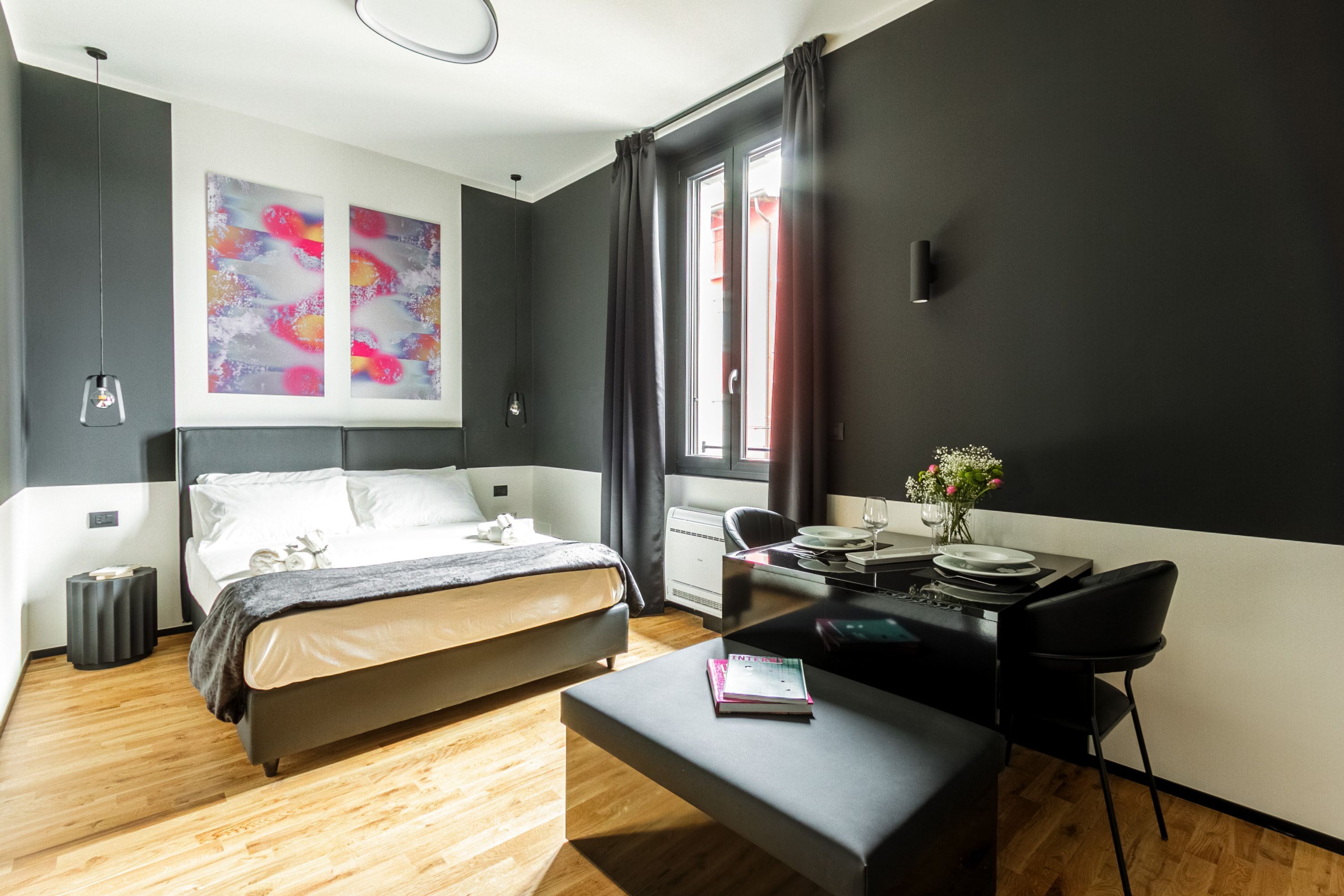 A modern bedroom with a bed, bedside table, and a desk with a chair.