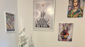 A living room with two blue armchairs, a glass coffee table with a white orchid plant, and three framed artworks on the wall. - Venini - Cozy 2 Bdroom Apartment in Loreto Area (Milan)