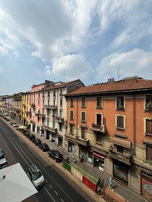 A row of colorful buildings along a street with parked cars and a clear sky. - Venini - Cozy 2 Bdroom Apartment in Loreto Area (Milan)