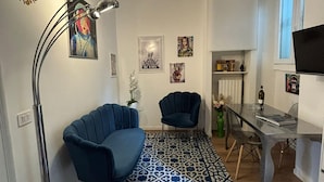 A modern living room with a patterned floor, two blue armchairs, a floor lamp, and artwork on the walls. - Venini - Cozy 2 Bdroom Apartment in Loreto Area (Milan)