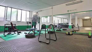 A gym with exercise equipment, a car, and a sign for Rentopolis. - Candiani F1 Bilocale (Milan)