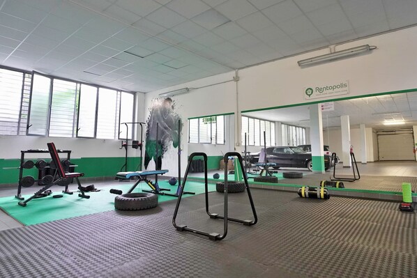 A gym with exercise equipment, a car, and a sign for Rentopolis. - Candiani F1 Bilocale (Milan)