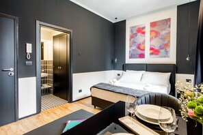 Une chambre d’hôtel moderne, équipée d’un lit, d’une table de chevet et d’un coin repas avec une table mise pour deux personnes.