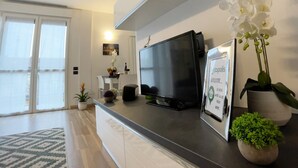 A modern living room with a flat-screen TV, a framed welcome sign, and decorative plants. - Candiani A3 Bilocale 2 Livelli (Milan)