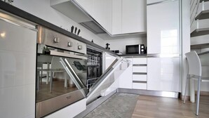 A modern kitchen with white cabinetry, a stainless steel oven, and a microwave. - Candiani A3 Bilocale 2 Livelli (Milan)