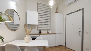 A modern kitchen with white cabinets, a wooden countertop, and a dining area with a white table and chairs. - Porta Vittoria - Cozy Stylish 1bdr in Duomo San Babila Area (Milan)