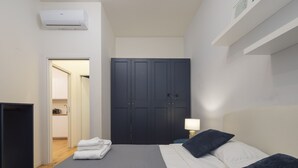 A hotel room with a bed, a wardrobe, a desk, and a bathroom visible through an open door. - Porta Vittoria - Cozy Stylish 1bdr in Duomo San Babila Area (Milan)