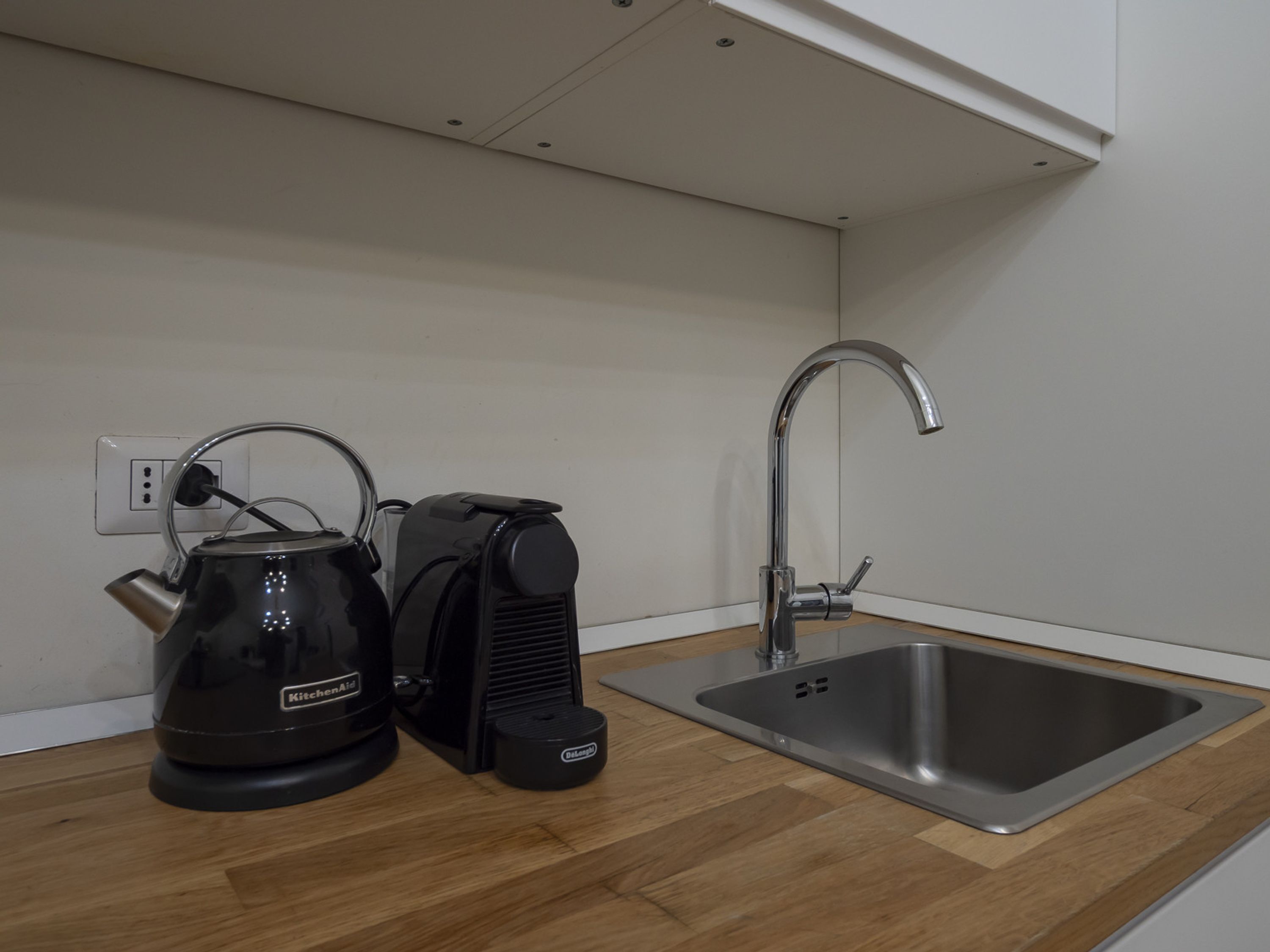A kitchen with a kettle, a coffee maker, and a sink.