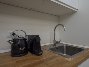 Une cuisine équipée d’une bouilloire, d’une machine à café et d’un évier.