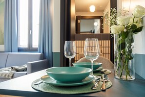 A dining area with teal plates, glasses, and a vase with white flowers. - Quantum 2 Quarks in Milano (Milan)