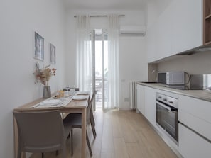 Une cuisine moderne avec un coin repas, comprenant une table en bois, des chaises, un four à micro-ondes et un four traditionnel.