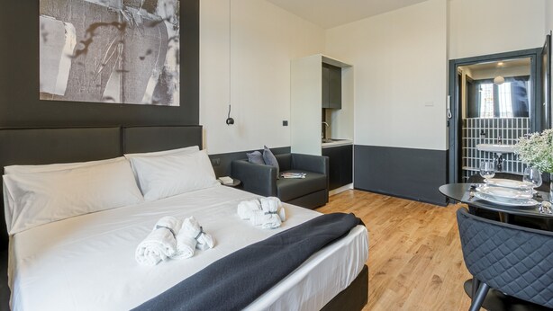 Une chambre d’hôtel moderne dotée d’un grand lit, d’un coin salon et d’une table à manger préparée pour deux personnes.