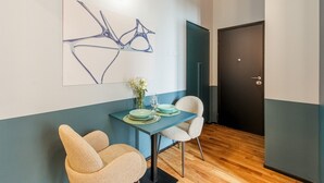 Un coin repas avec une table dressée pour deux personnes, un vase rempli de fleurs et un tableau abstrait moderne accroché au mur.