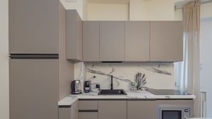 Una cocina moderna con microondas integrado, cafetera y lavamanos.