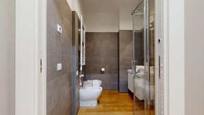 Un baño moderno con inodoro, bidé y cabina de ducha de vidrio.