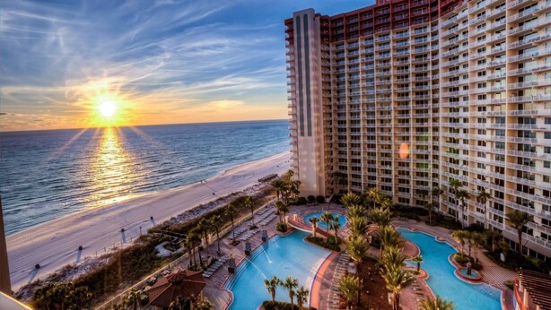 Ein Hochhaus-Hotel mit Poolbereich und Blick auf den Strand.