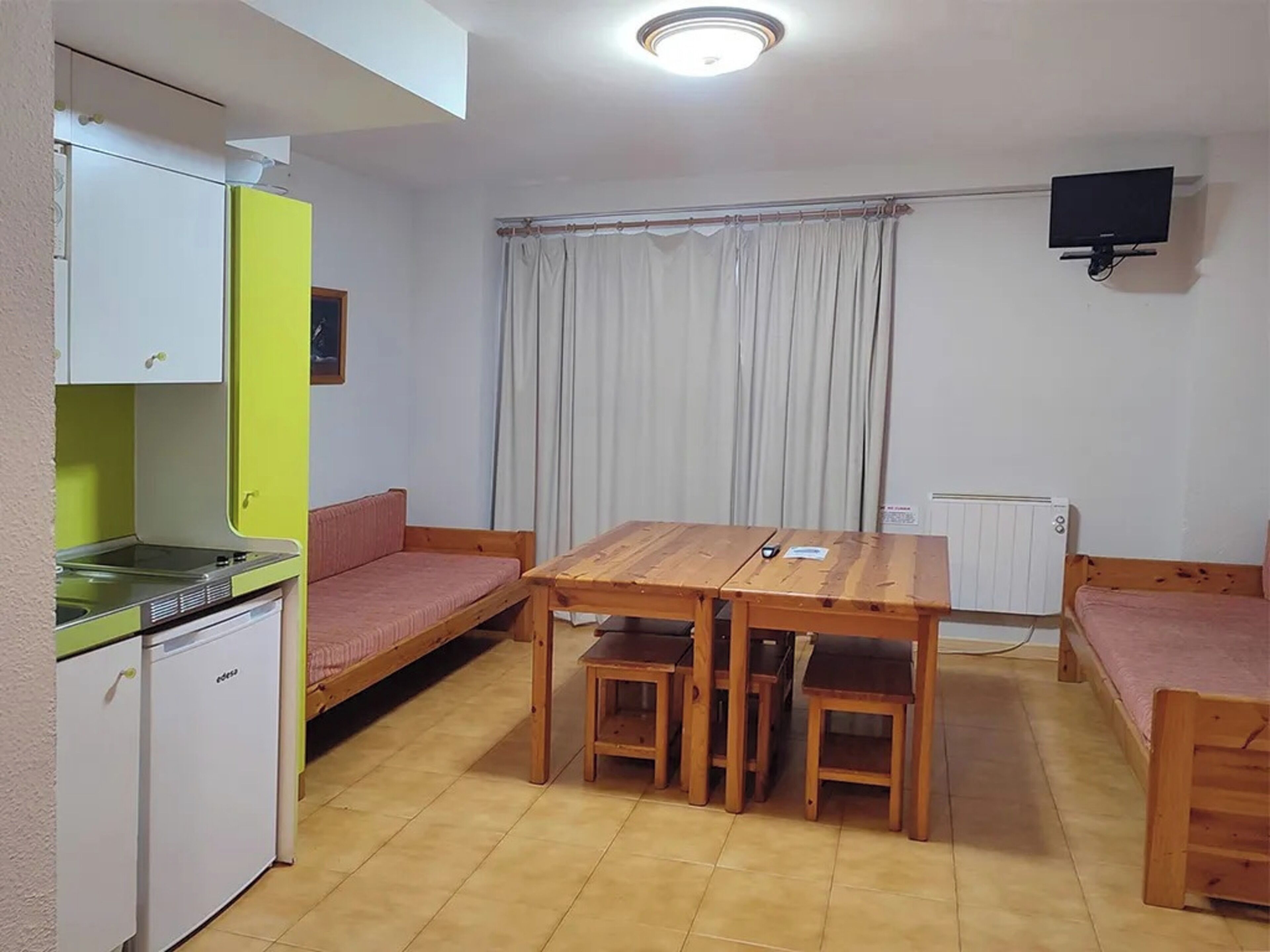 Una habitación compacta con kitchenette, una mesa de comedor con sillas, un sofá y una cama.