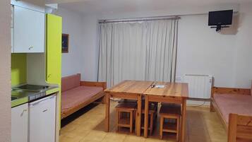 Una habitación compacta con kitchenette, una mesa de comedor con sillas, un sofá y una cama.