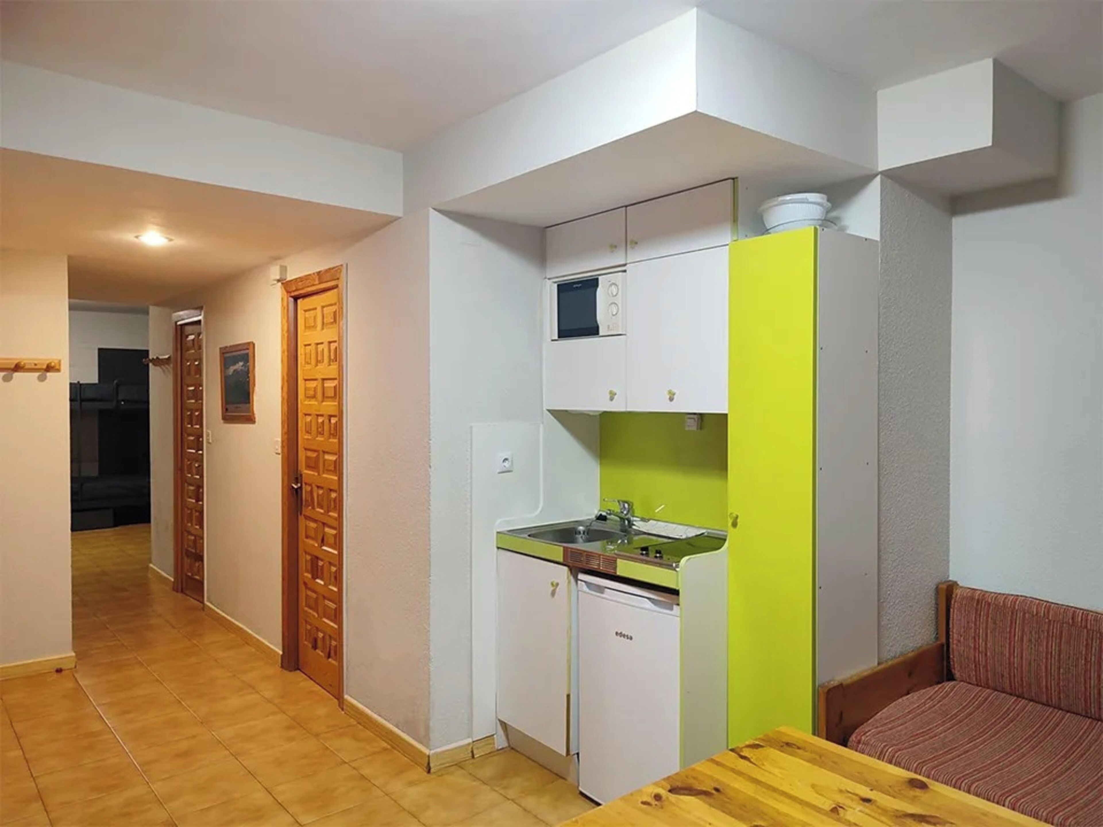 A compact kitchen with white and green cabinets, a small sink, and a dishwasher.
