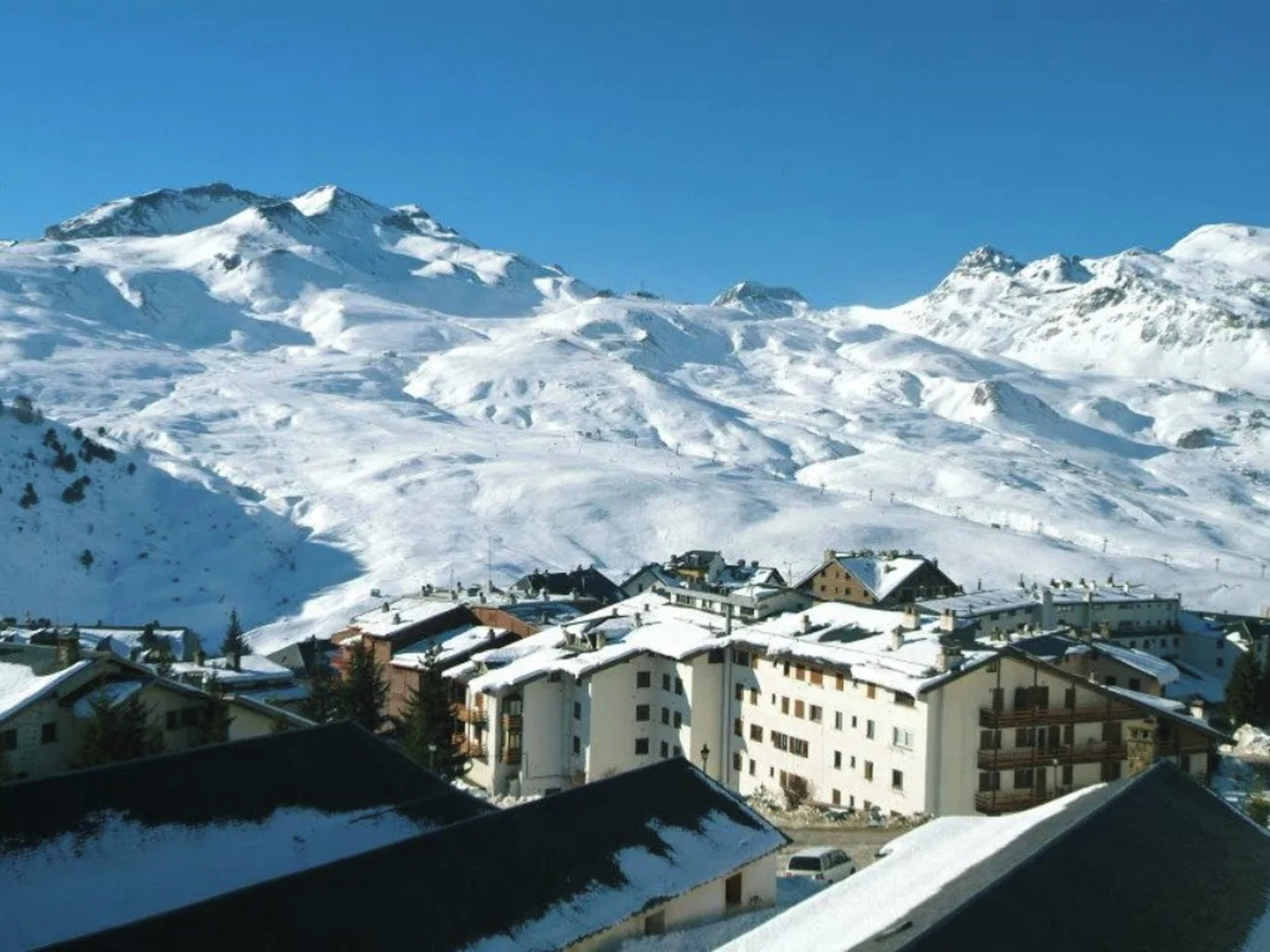 A snow-covered mountain town with buildings and a clear blue sky.