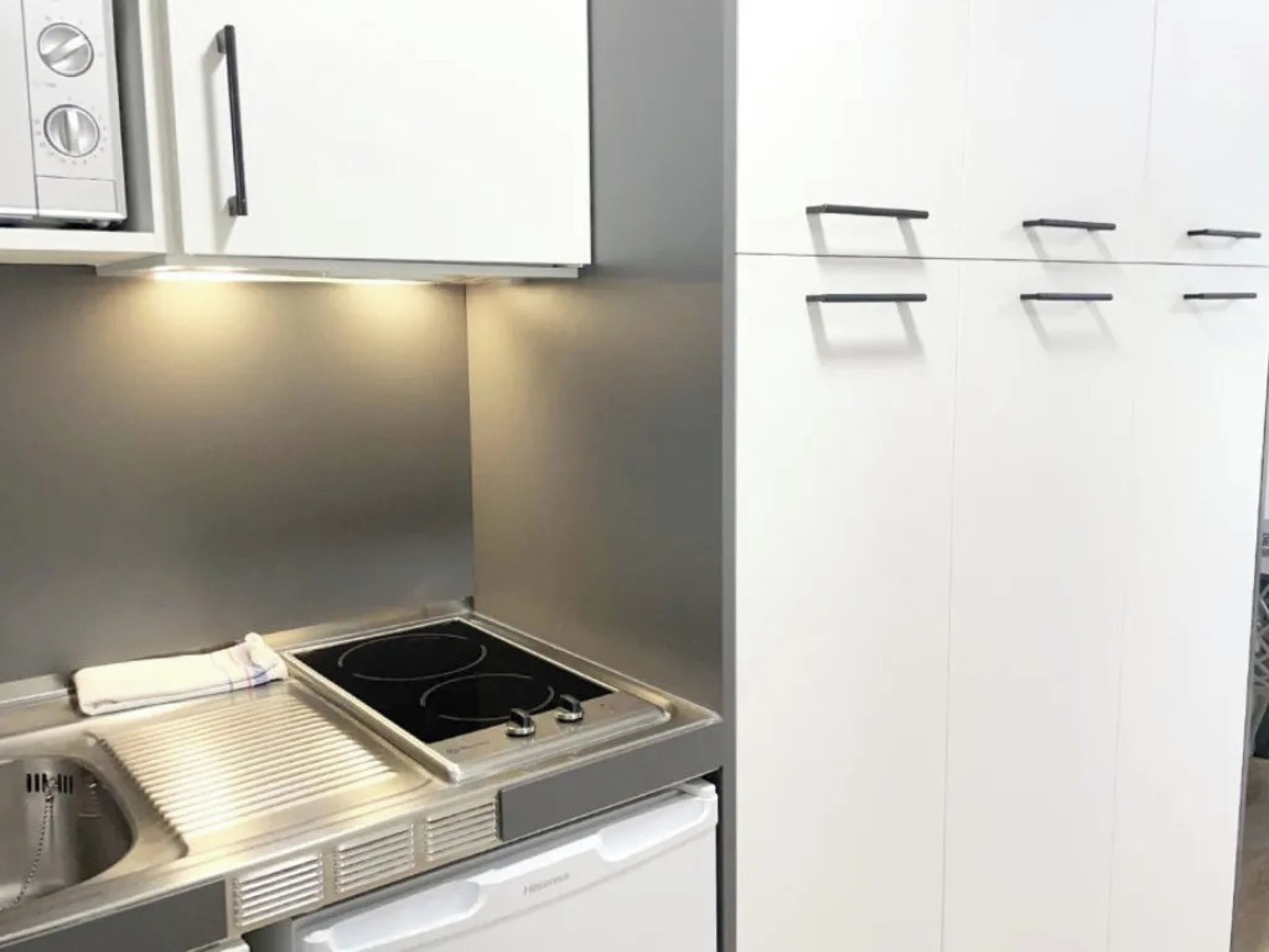 A modern kitchen with a built-in stove, a sink, and white cabinetry.