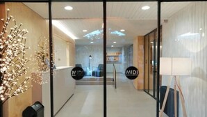 A modern hotel lobby with glass doors, a reception desk, and a seating area.
