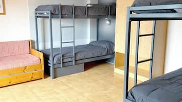 Een studentenkamer met stapelbedden, een houten bank en betegelde vloer.