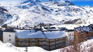 A snow-covered mountain town with buildings and a prominent mountain in the background.