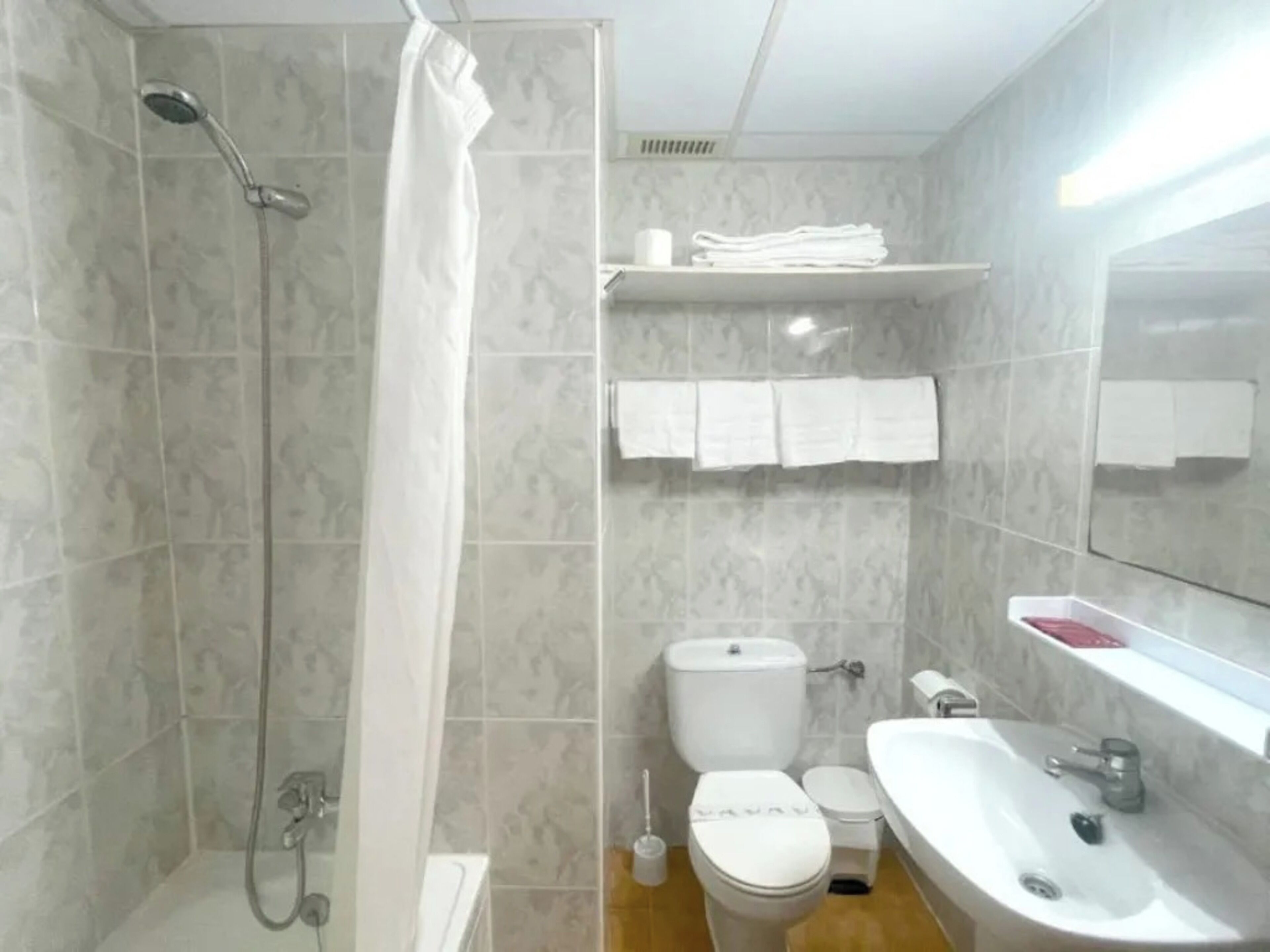 Un bagno con doccia, servizi igienici, lavandino e specchio.